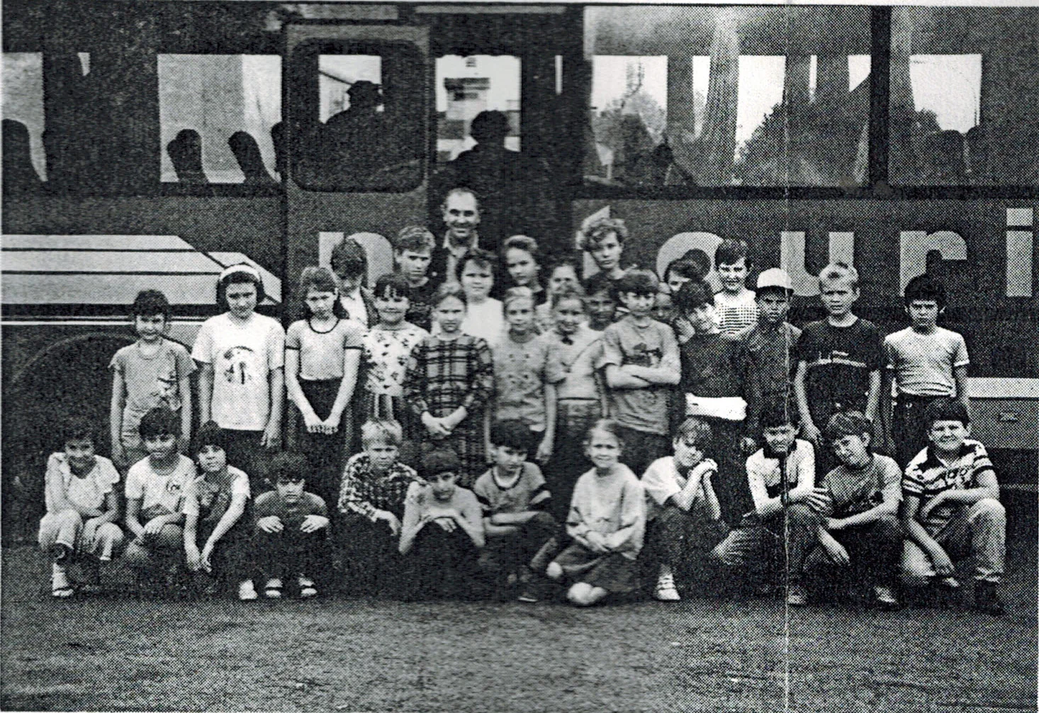 Archivaufnahme einer Kindergruppe vor einem Bus