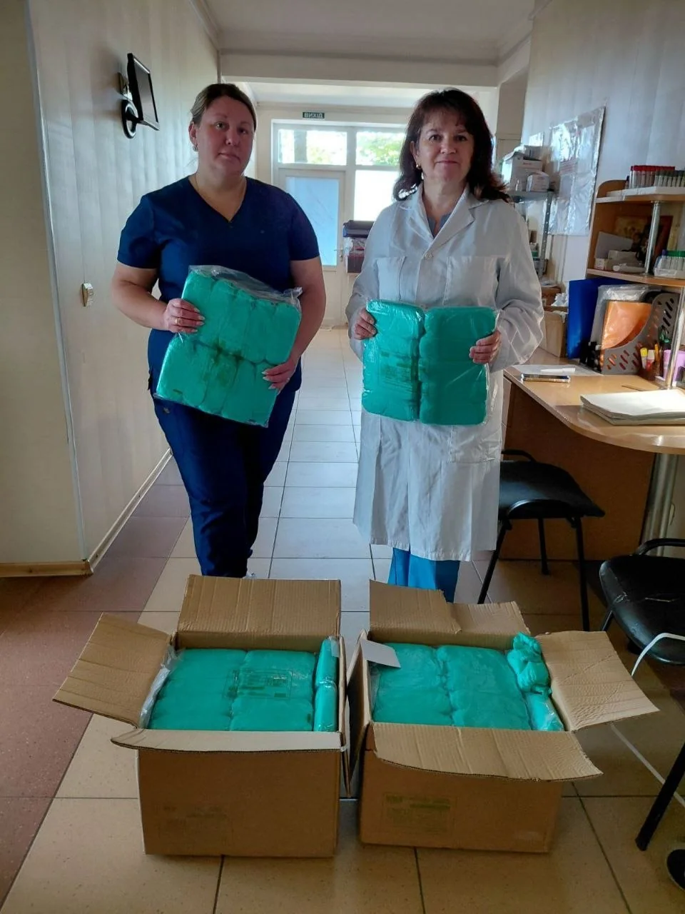 Zwei Frauen zeigen Packungen mit medizinischen Materialien
